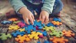 Child's hands placing colorful puzzle pieces on wooden floor. Autism concept