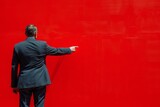 Fototapeta  - Man in Suit Pointing at Red Wall