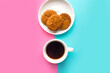 Coffee cup and raisin cookies on blue and pink pastel background. Minimal concept
