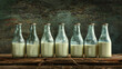 A row of milk bottles are lined up on a wooden table