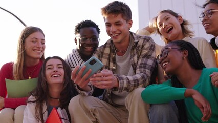 Wall Mural - A large multiracial group of teenagers taking a selfie looking front camera laughing and having fun piggybacking together outdoor. Young students enjoying their free time with friends in street city