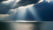 Dramatic interplay of light and shadow: sunbeams pierce clouds over a vast ocean