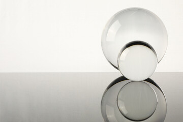 Sticker - Transparent glass balls on mirror surface against light background. Space for text