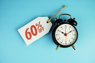 Wall Mural - Top view of Sale 60% text on tag sale with black alarm clock flat lay on blue background