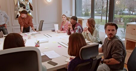 Wall Mural - In a modern office setting, a group of multiracial business employees collaborate and discuss around a conference table, showcasing their teamwork and collective effort in achieving common goals.