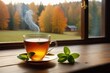 A glass cup of hot tea with mint leaves on a wooden table beside a window, cozy background, horizontal composition