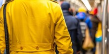 A Commuter Wearing A Yellow Raincoat Navigating Through The Subway Station