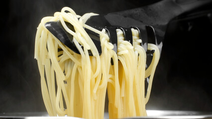 Wall Mural - Cooking pasta in boiling water. Chef takes spaghetti out of the boiling water