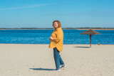 Fototapeta Londyn - Vacation mood. Plus size happy mature lady wear yellow shirt and blue pants at beach , spring - summer clothes collection