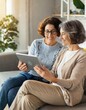 © Marko - Side view an adult daughter and a senior mother spend time with a tablet indoor, a young woman showing to mature mom smth in a network, helps to figure out with a device