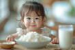 Little child learning to eat rice and milk