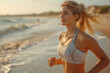 Side view shot of beautiful young woman in sportswear jogging on beach. Female runner jogging on outdoors on beach. 
