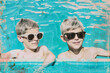 Pop collage Illustration of two young boys wearing sunglasses and standing in a pool.