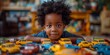 In a charming portrait, a playful black boy sits amidst lined-up colorful toy cars, exuding innocence and joy.