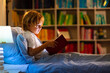 © famveldman - Child reading book in bed. Kids read at night.