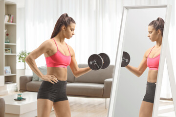 Sticker - Fit young female exercising with a dumbbell in front of a mirror