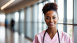 Young black female doctor in soft pink scrubs, smiling looking in camera, Portrait of woman medic professional, hospital physician, confident practitioner or surgeon at work. blurred background