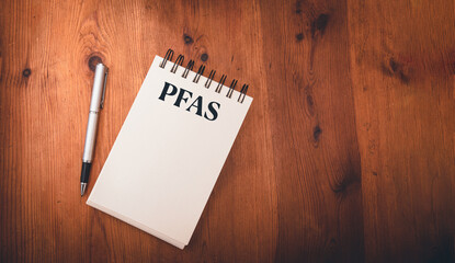 note pad on wooden table with pfas, per- and polyfluoroalkyl substances , concept of eternal or fore