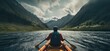 Witness the exhilaration of outdoor adventure as a young man navigates whitewater rapids in a kayak, amidst the rugged beauty of mountain scenery.