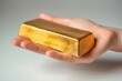 Hand holding a gold bar isolated on a white background