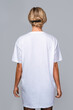 Woman dressed in a white oversized t-shirt with blank space, ideal for a mockup, set against gray background