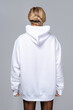 Woman dressed in a white oversized hoodie with blank space, ideal for a mockup, set against gray background