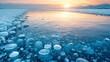   Ice-covered water with bubbles beneath a cloudy sky, sun setting beyond mountains