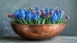   Copper bowl with blue flowers on a wooden table against a gray background