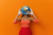 Woman holding globe with gloves on orange background in educational concept