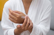 Self-pampering: In her bathrobe, a woman relishes a body skincare ritual, applying moisturizing cream to her hand in a close-up. 