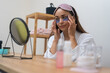 Home spa indulgence: A lady in a bathrobe applies eye patches, focusing on her anti-aging skincare routine while looking in the mirror during a spa day. 
