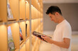 Asian young man hold and read magazine at bookshelf in library. side view