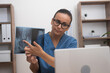 doctor in blue uniform pointing finger on x-ray film showing to patient in laptop during online tele medicine consultation