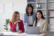 © amnaj - Three asian businesswoman are sitting at a desk with a laptop open