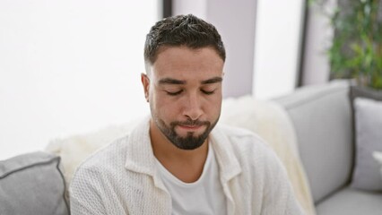 Poster - Upset young arab man frowning on home sofa, the nervous skeptic burdened with problems in his indoor lifestyle, grappily embracing a negative headspace.