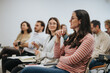 © qunica.com - Group of attentive employees listening to a speaker at a seminar. A woman in foreground looks engaged, taking part in discussion.