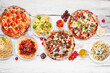 Delicious Italian food table scene. Selection of pizzas and pastas. Top down view on a white wood background.