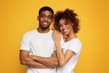 Wall Mural - Young african-american couple posing on orange background