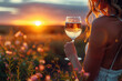 A silhouette of a person holding a glass of wine, against the backdrop of a sunset
