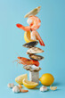 А stack of fresh seafood, clams, crab, oysters, shrimps, surrounded by garlic and lemon on pastel pink background. Minimal food still life concept.	