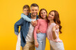 Family with father mother children hugging on yellow background
