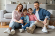 © Prostock-studio - Happy family sitting together on floor at home