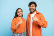 Thumbs up gesture by cheerful couple on blue