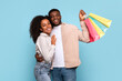 Happy couple hugging with shopping bags on blue background