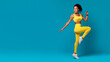 Energetic woman in mid-motion running pose on blue background