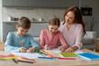 © Prostock-studio - Mother and two kids drawing together at home