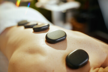 Poster - Woman having hot stone massage and laying on massage table