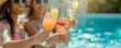 Women clinking glasses with cocktails at poolside