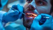 An intense blue-hued close-up captures a man undergoing a dental procedure, with the dentist's hands expertly navigating dental tools in his mouth.