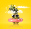 Pineapple with ring float and sunglasses on a yellow background. Creative concept summer beach holiday